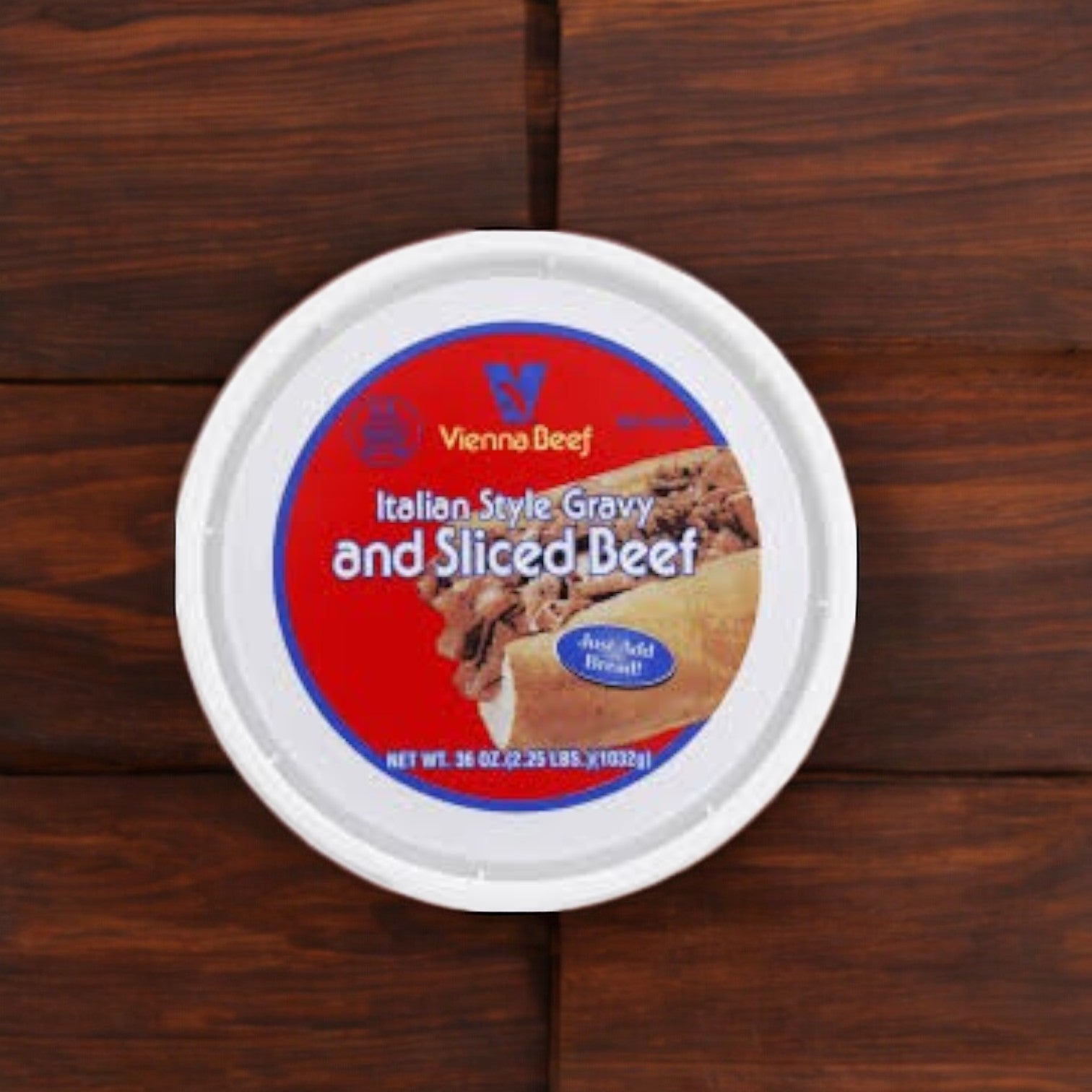 A round container labeled "Vienna Beef Italian Style Gravy and Sliced Beef-36oz-3 Count" rests on a wooden surface, ideal for preparing authentic Chicago-style Italian beef sandwiches.