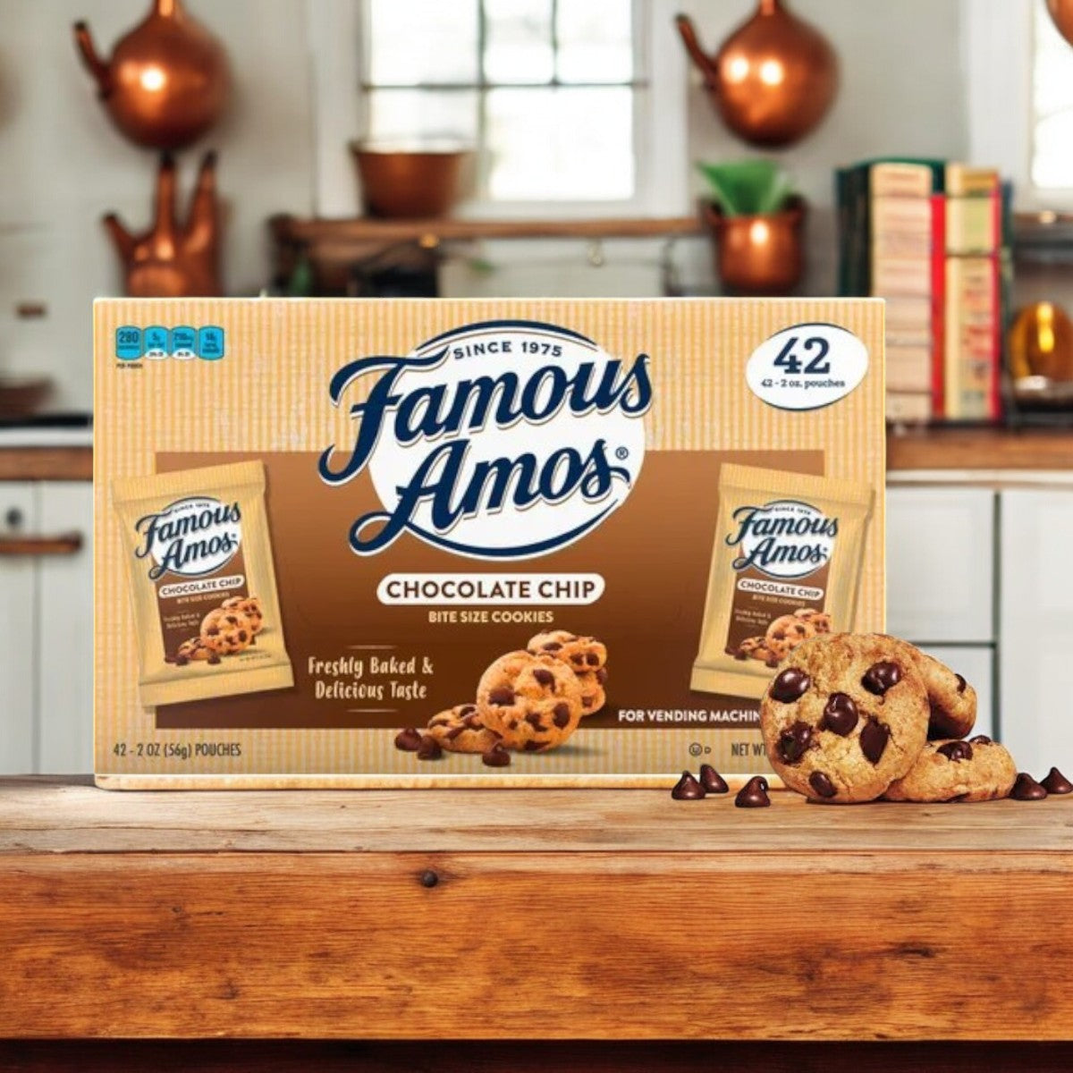 A box of Famous Amos Chocolate Chip Cookies-42 Pack-1 Count is on a wooden counter in a cozy kitchen, surrounded by bite-sized treats and scattered chocolate chips.