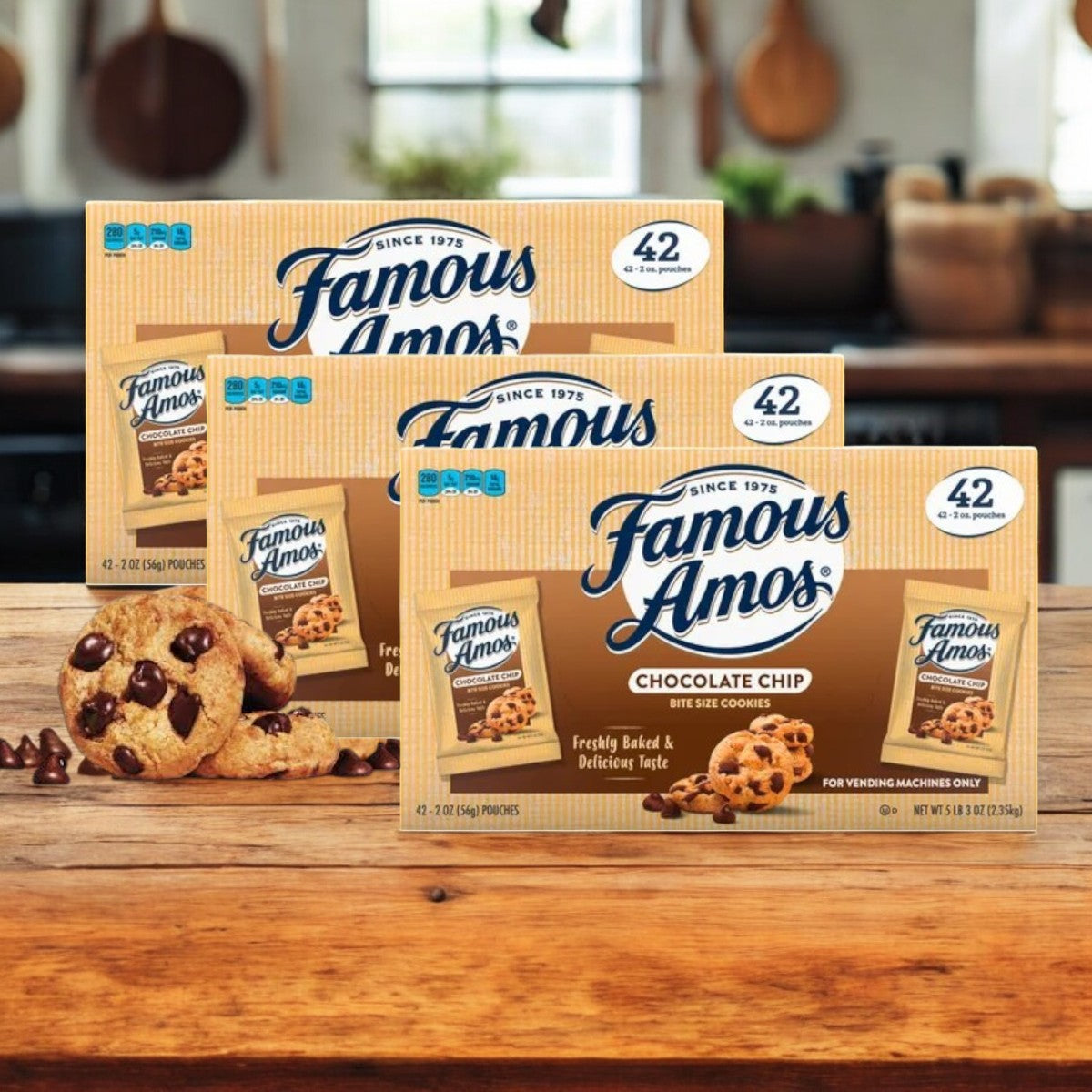 Three cases of Famous Amos Chocolate Chip Cookies-42 Pack are on a wooden table. These perfect crunchy snacks make any moment sweeter.