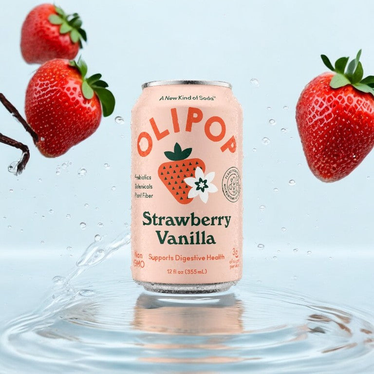 A can of OLIPOP Prebiotic Soda, Strawberry Vanilla (12 fl oz), surrounded by floating strawberries and splashing water, promotes digestive health with prebiotics and is labeled non-GMO with just 3g of sugar per serving.