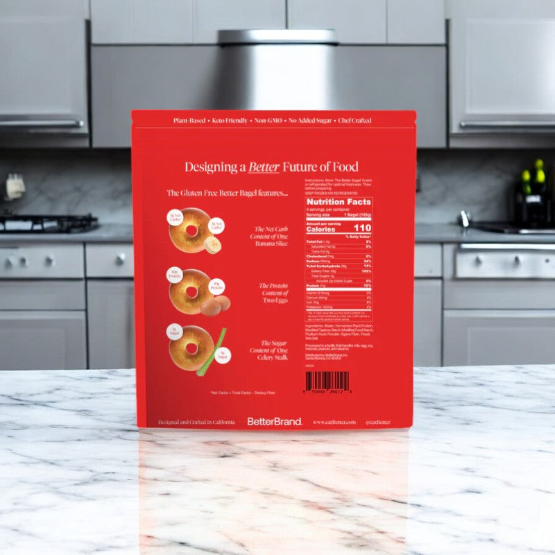 A box of "Better Brand - The Gluten Free Better Bagel" sits on the marble kitchen counter, displaying nutritional facts and features on the back. With their soft and chewy texture, these bagels are perfect for creating versatile meals any time of day.