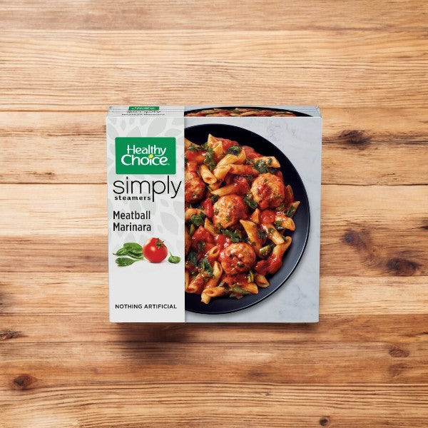 A package of Healthy Choice Simply Steamers Meatball Marinara, 10 oz., is displayed on a wooden background. The box showcases an appetizing image of the meal with meatballs, marinara sauce, and pasta, and prominently features the message "Nothing Artificial.