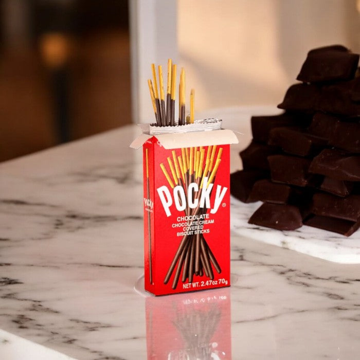 A box of Pocky Chocolate Cream Covered Biscuit Sticks rests on a marble countertop, with a stack of chocolate pieces in the background, showcasing the delightful Pocky's enticing chocolate coating.