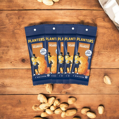 Five bags of Planters Honey Roasted Peanuts, each weighing 1.5 ounces, are elegantly arranged in a fan shape on a rustic wooden surface, with scattered peanuts adding a touch of charm. Mr. Peanut's iconic presence is felt in every delicious bite of these irresistible snacks from Planters.