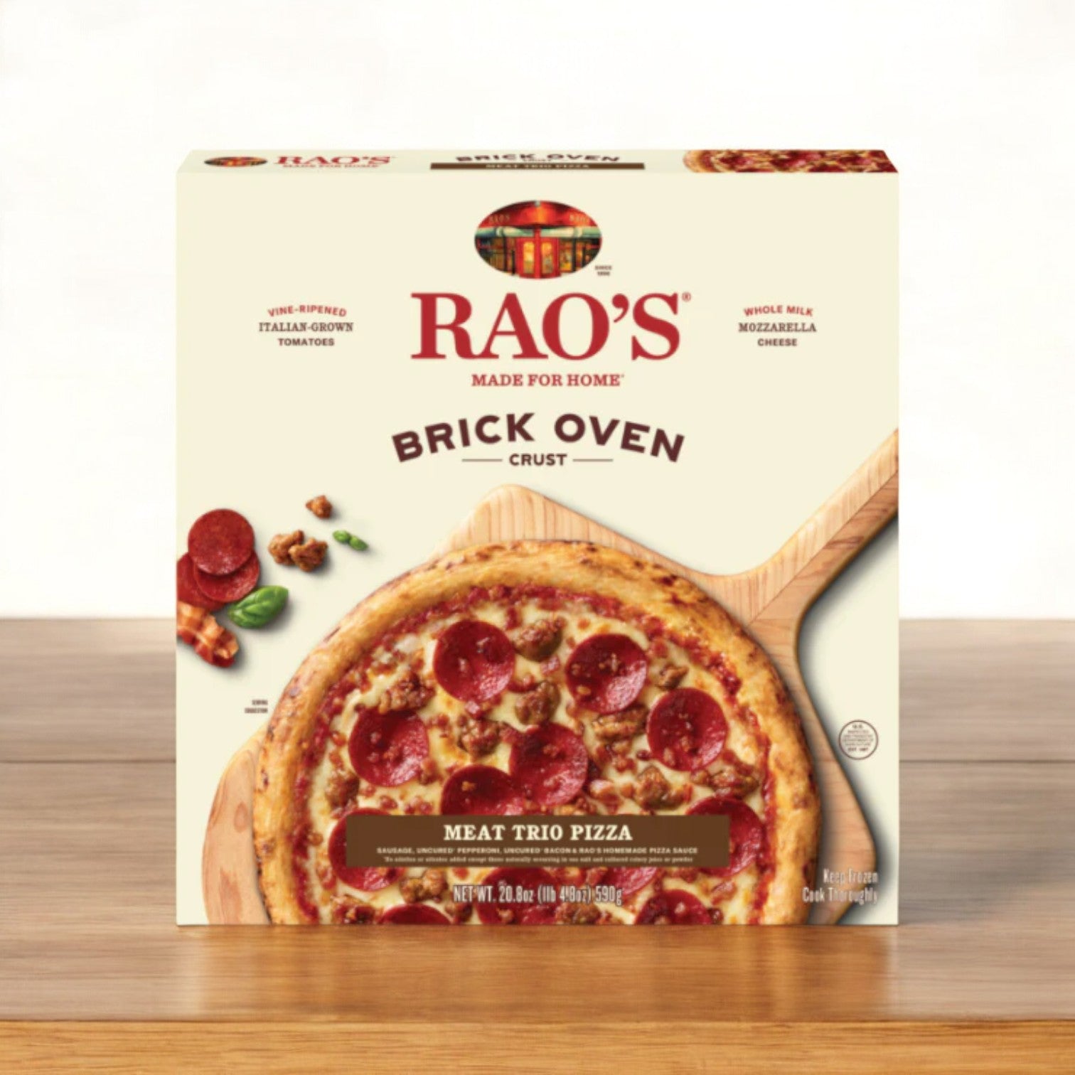 A box of Rao's Meat Trio Frozen Pizza- 20.8 oz is displayed on a wooden surface, showcasing an image of the ready-to-bake pizza topped with pepperoni, sausage, and bacon.