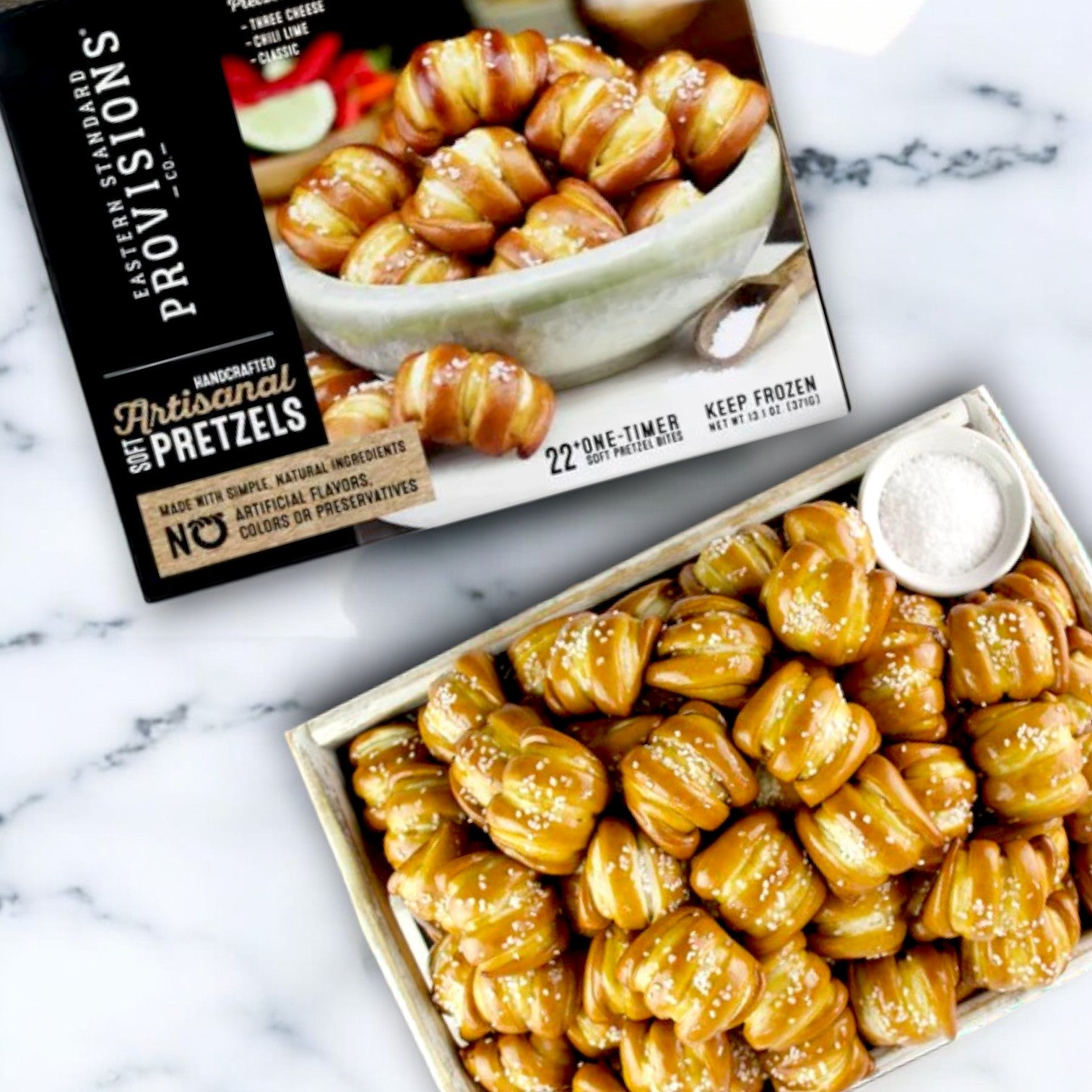 A tray of Eastern Standard Provisions Pretzels, Soft, Artisanal, Handcrafted sits on a marble surface beside their box. Each lightly salted bite has an irresistibly soft and chewy interior.