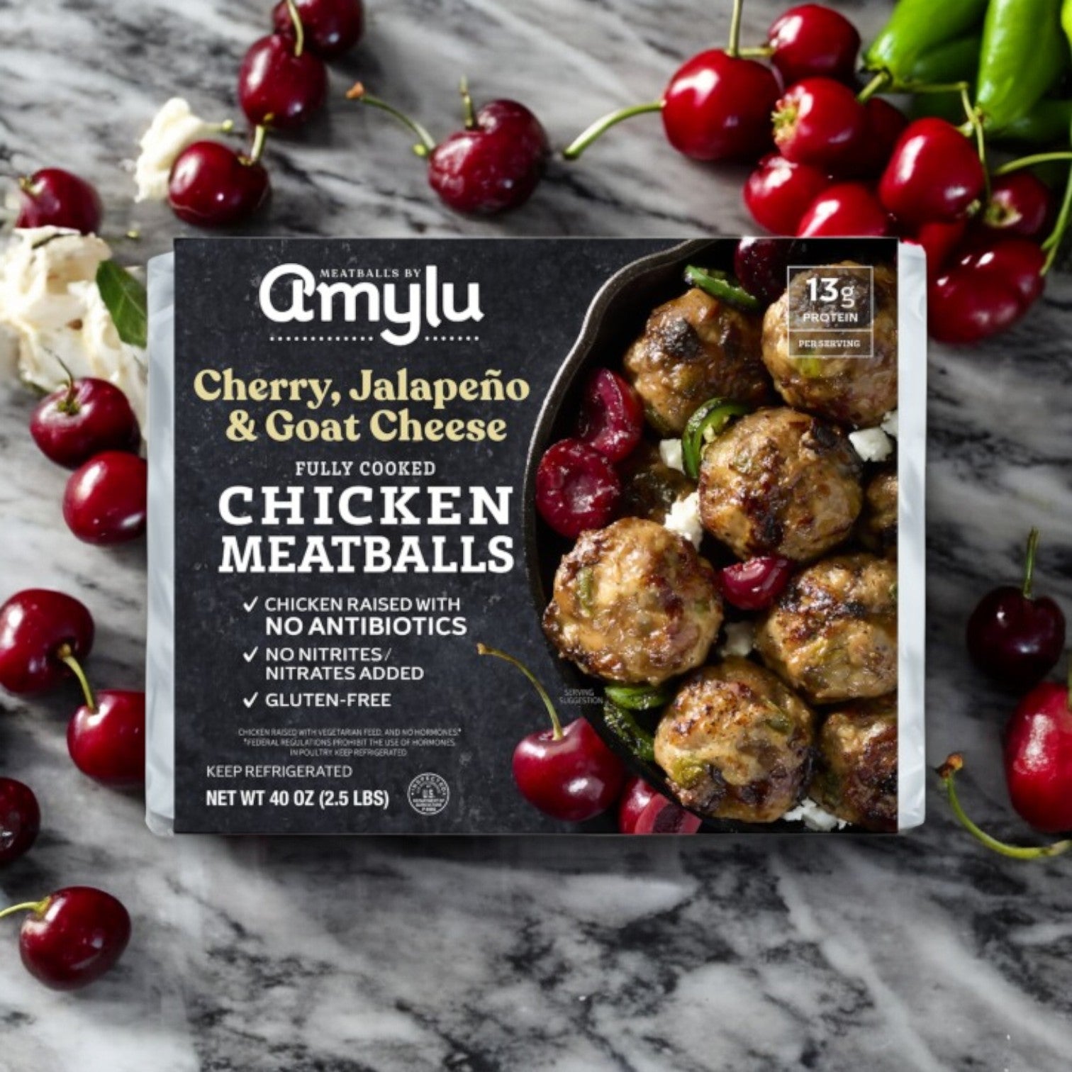 Easy Lunches Amylu Cherry, Jalapeno, and Goat Cheese Chicken Meatballs, 40 oz, 3 Packs displayed on marble with fresh cherries and jalapeños highlights these uniquely seasoned chicken meatballs.