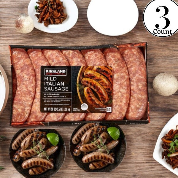 A pack of Kirkland Signature Mild Italian Sausage-3 Count rests on a wooden surface, complemented by two plates of cooked sausages infused with Italian herbs and spices, garnished with herbs and lime. Three whole onions and pecans are artfully arranged around the plates for a touch of rustic charm.