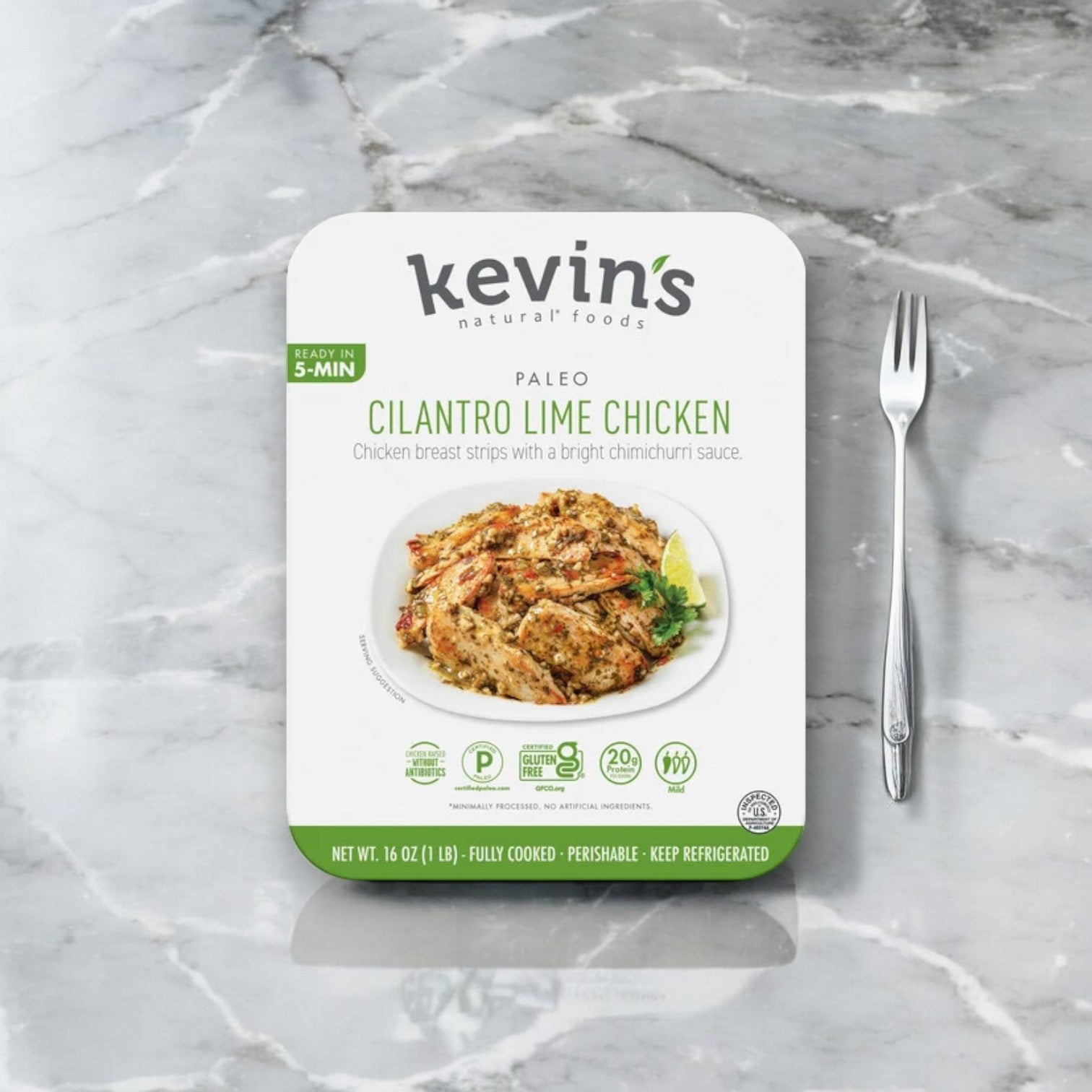 A package of Kevin's Cilantro Lime Chicken - 1 Box 16 oz is displayed on a marble surface next to a fork. The pre-cooked meal, from the brand Kevin's, highlights "Ready in 5 Min" and contains marinated chicken breast strips in chimichurri sauce.