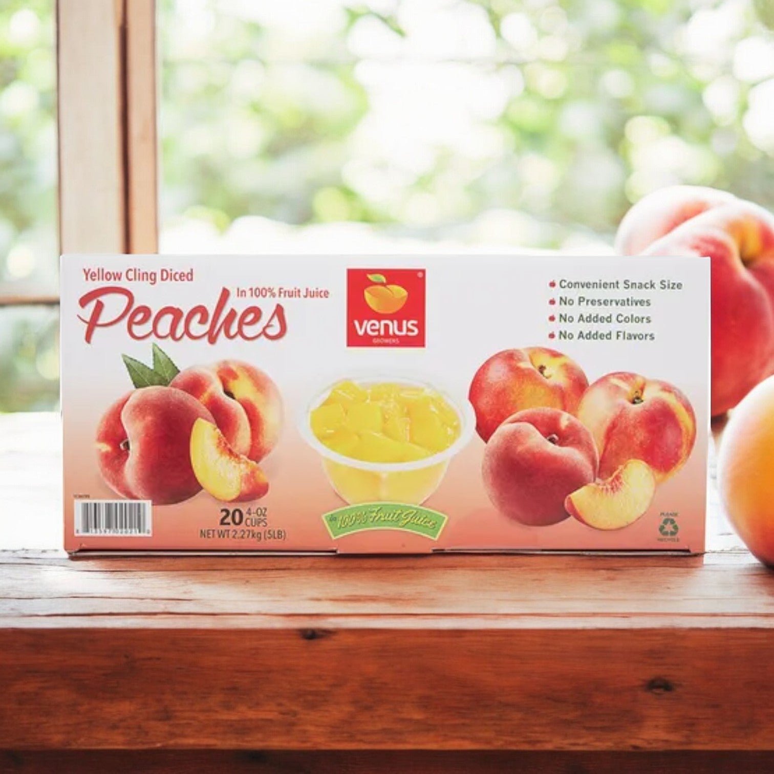 A package of Easy Lunches' Venus Growers Diced Peach Cups, 4 oz each, in a set of 20, placed on a wooden table with a blurred outdoor background.