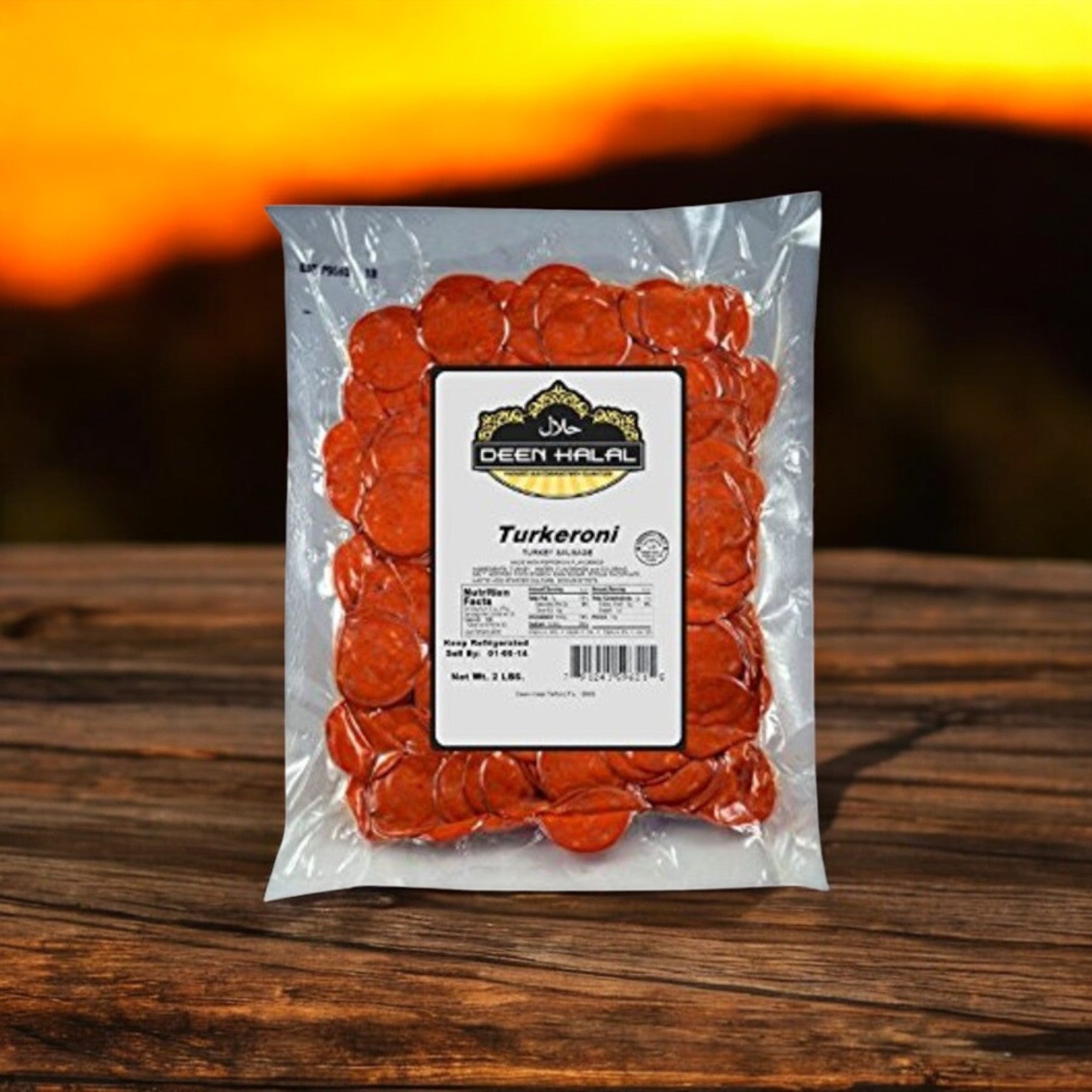 A 2 lb. pack of Deen Halal Turkeroni slices, made from premium turkey meat, rests on a wooden surface with a sunset backdrop.