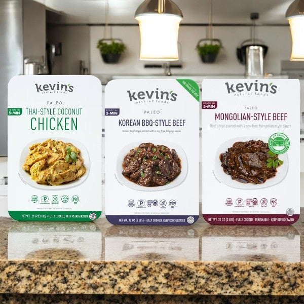 Three packets of Easy Lunches' Kevin's Meals 32 oz Bundles, featuring Thai-Style Coconut Chicken, Korean BBQ-Style Beef, and Mongolian-Style Beef on a kitchen countertop, showcasing delicious chef-prepared meals inspired by global cuisines.