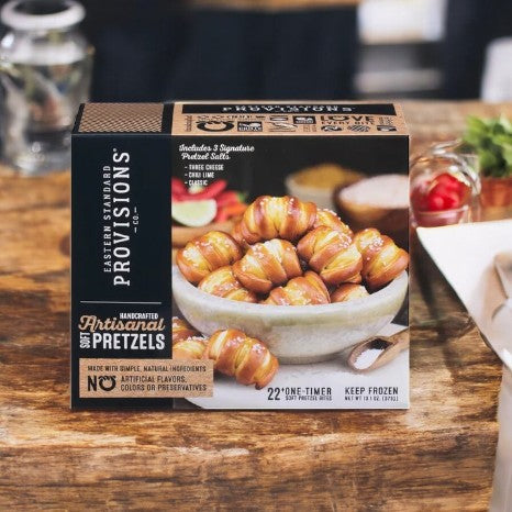 On a wooden table rests an "Eastern Standard Provisions Pretzel Bites - 1 Count" box, brandishing high-quality ingredients and promising a delightful chewy snack experience with its front display of Pretzel Bites.