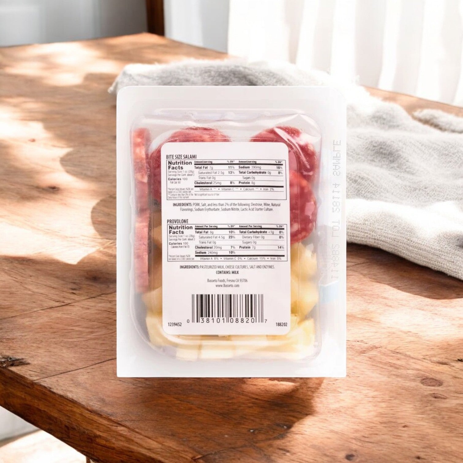 Busseto's California Snackin' tray with bite-size salami and provolone cheese is placed on a wooden table, sunlight streaming in. It's a protein-rich option ideal for a quick and satisfying snack.