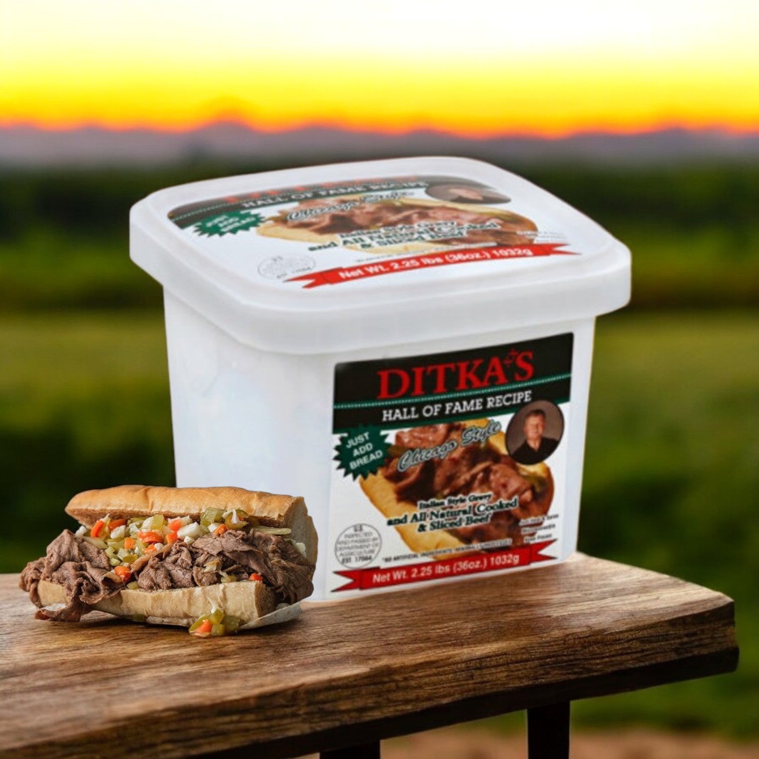 A container labeled "Ditka's Italian Beef, Chicago Style (2.25 lb.)" by Vienna Beef sits on a table beside a sandwich filled with Ditka's Italian Beef and diced vegetables, with a blurred sunset view in the background.