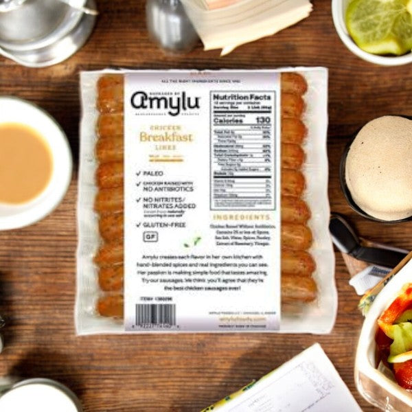 Amylu Chicken Breakfast Sausage Links, made with all-natural ingredients, are arranged on a table alongside coffee, a fresh salad, a notebook, and a sandwich.