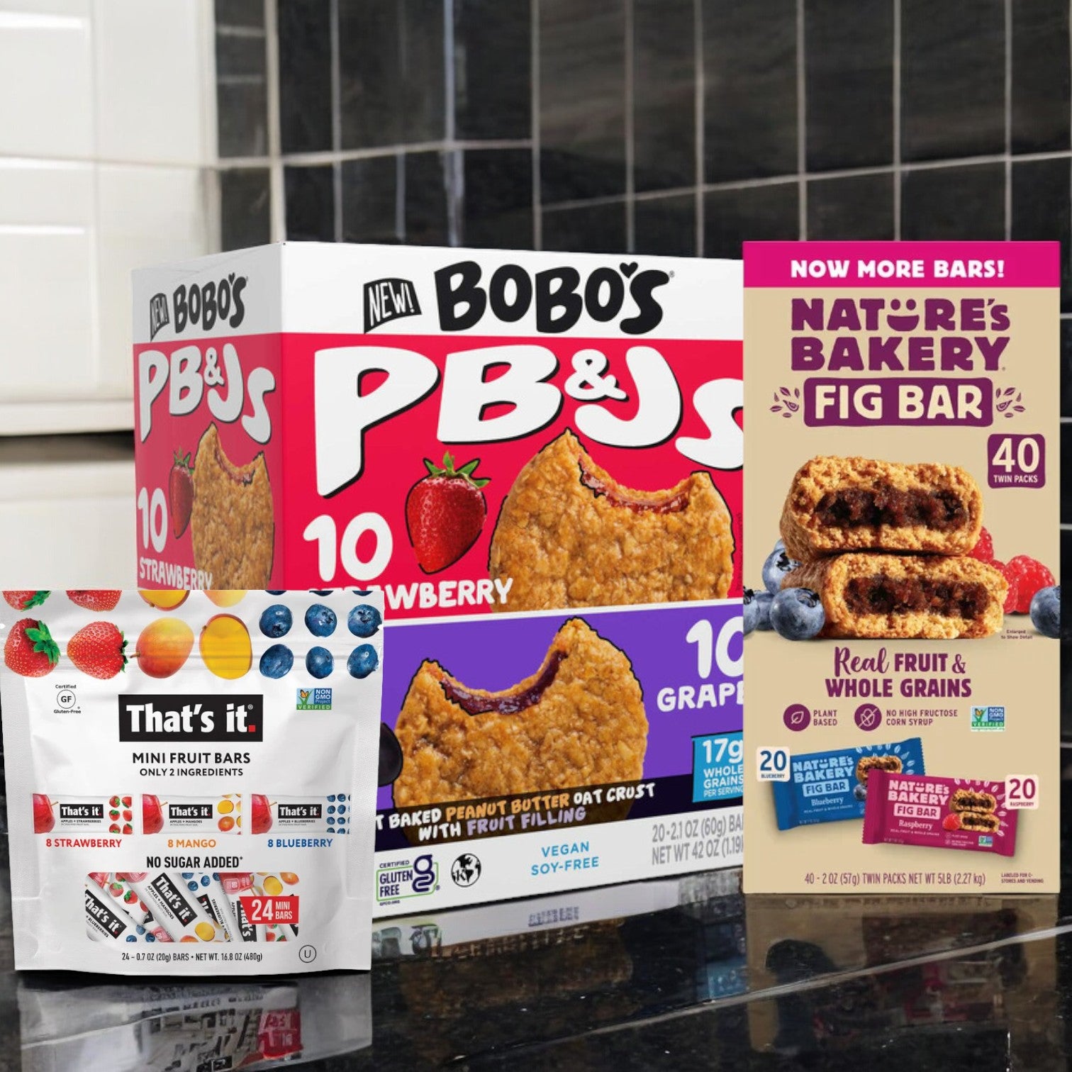 A neatly arranged assortment of snack bars from Easy Lunches sits on the kitchen counter, offering the perfect variety for school lunches. The Kids Essential Lunch Pack includes 24 That's It Mini Fruit Bars, 20 Bobo's PB&J Strawberry and Grape Bars, and 40 Nature's Bakery Fig Bars—nutritious snacks that are ideal for a kids' lunch pack.