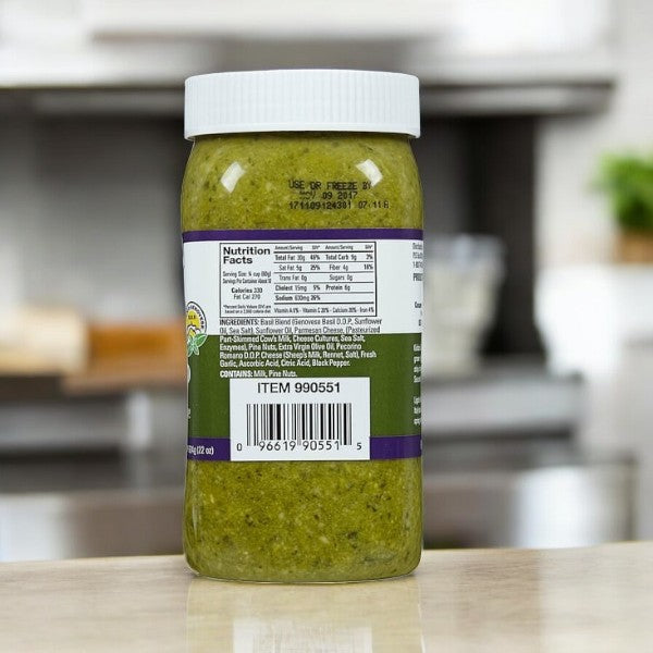 A jar of Kirkland Signature Imported Basil Pesto from Easy Lunches sits on the kitchen countertop, with its label showing nutrition facts and a barcode. Its vivid green hue adds gourmet flair to your culinary creations.