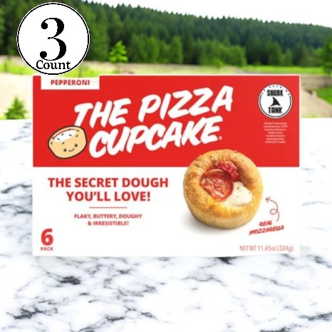 A box of The Pizza Cupcake Pepperoni-3 Count sits on a marble surface. The packaging boasts "The Secret Dough You'll Love" along with its Shark Tank branding, clearly highlighting a delightful snack experience from The Pizza Cupcake brand.