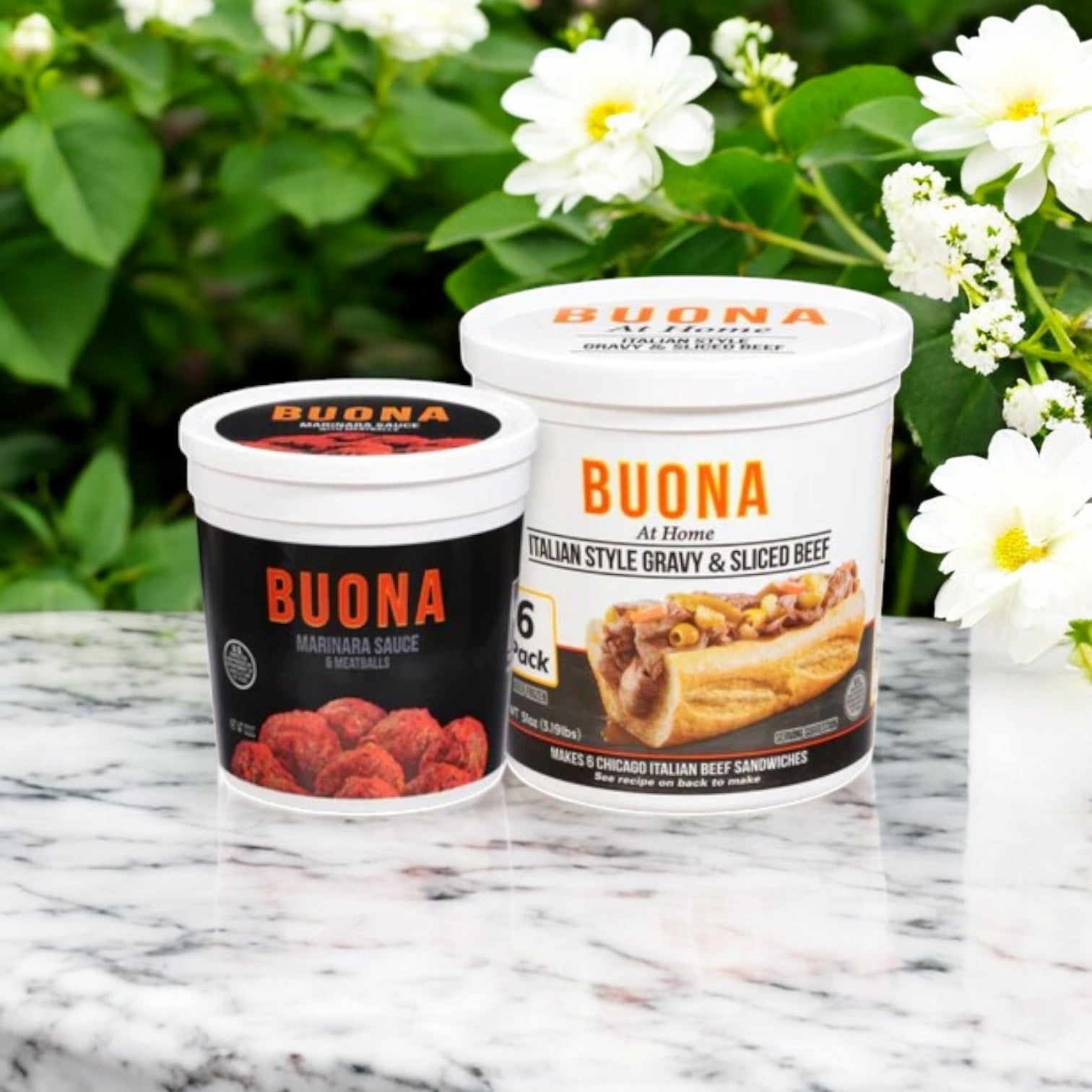 Buona's Marinara Sauce & Meatballs Kit with Italian Beef is artfully arranged on a marble surface among white flowers, evoking the flavors of a classic Chicago-style beef experience.