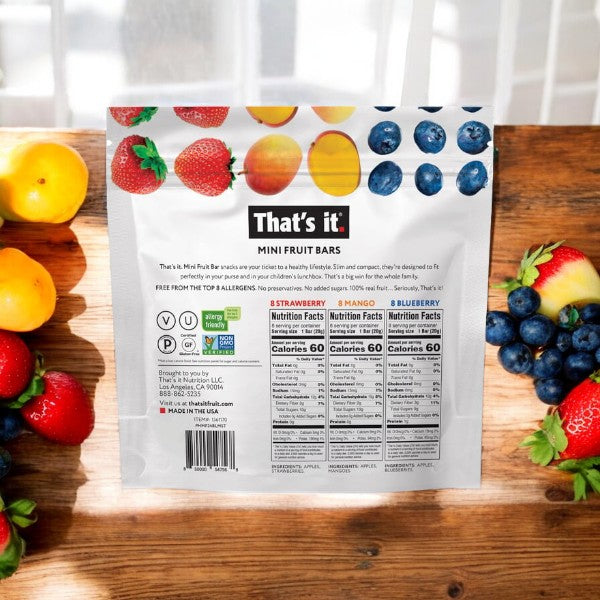 Back of an "Easy Lunches That's it Mini Fruit Bars, 24-count - 3 Bags- 72 Total Bars" package featuring strawberries, mangos, blueberries, and nutrition facts, surrounded by fresh fruits on a wooden surface.