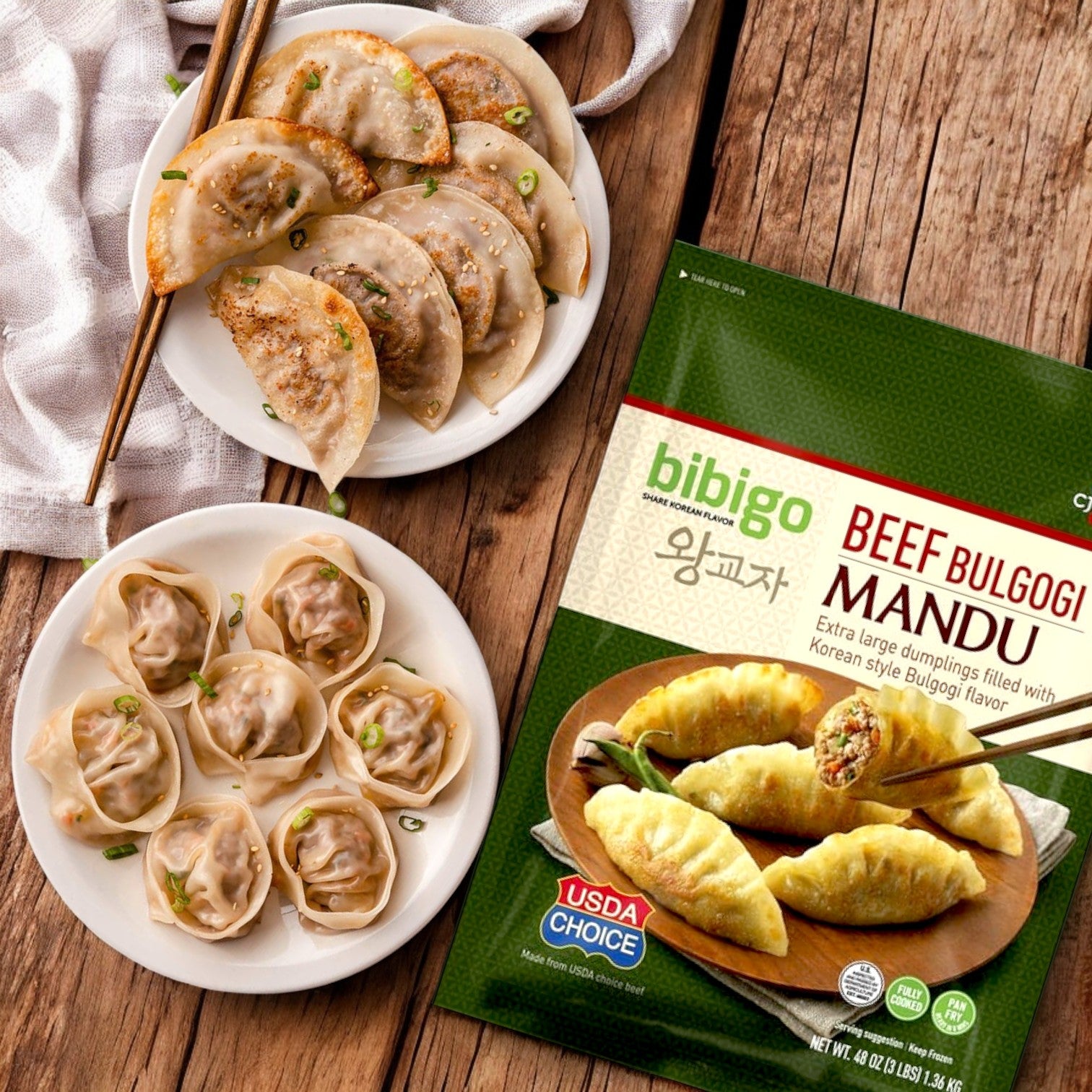 Two plates of Korean-style dumplings are beside a package of CJ Bibigo Beef Bulgogi Mandu Dumplings – 3 lbs, topped with chopped green onions, highlighting the deliciousness of Bibigo Steamed Dumplings.