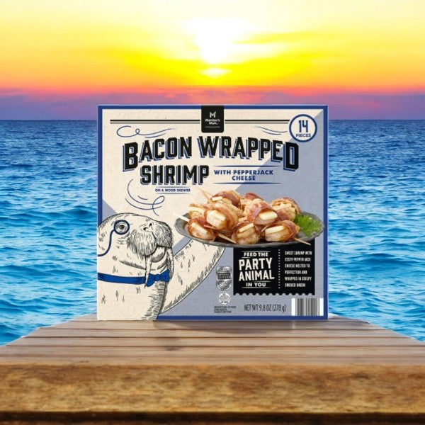 The Member's Mark Bacon Wrapped Shrimp with Pepper Jack Cheese (2.37 oz, 1 count) is perfectly showcased on a wooden dock, illuminated by the hues of a sunset over the ocean. Delight in top-tier products that deliver gourmet flavors to your table.