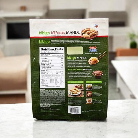 The Bibigo Beef Bulgogi Mandu- 1 Count package by bibi features nutritional info and details on a kitchen counter, emphasizing the savory Korean dumplings' authentic bulgogi marinade.