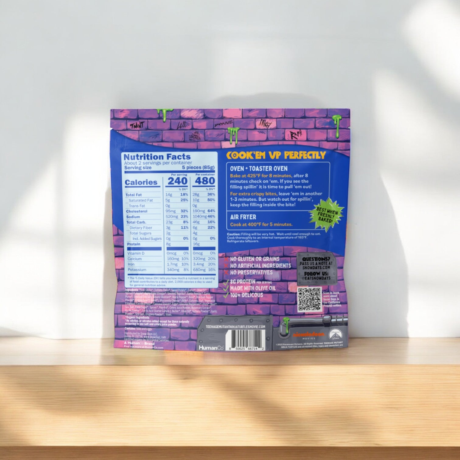 A package of Snow Days Uncured Pepperoni Pizza Bites, Gluten Free, Grain Free, 6 oz. - part of a 3 bag total, rests on the wooden surface. The packaging prominently displays cooking instructions and nutrition facts to keep you informed.