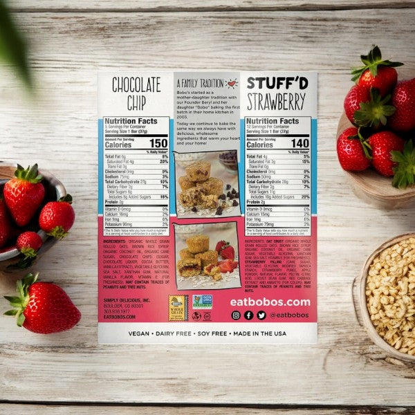 Back of an Easy Lunches box featuring Bobos Oat Mini Bites product information and images of Chocolate Chip and Stuff'd Strawberry flavors, showcasing wholesome ingredients on a wooden surface with strawberries, a bowl of oats, and individually wrapped Bobos Oat Mini Bites for convenience.