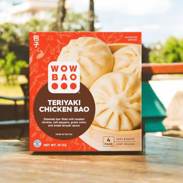 A box of Wow Bao Teriyaki Chicken Bao by Wow Bao on an outdoor table spotlights the enticing steamed buns depicted on the packaging. This Asian-inspired snack contains four frozen delights to transport your taste buds to new horizons.