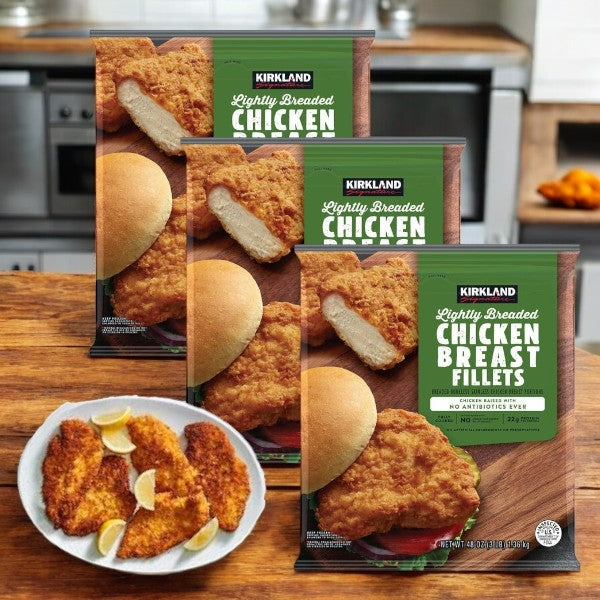 On the kitchen counter are four boxes of Kirkland Signature Lightly Breaded Chicken Breast Fillets, ideal for high-protein meal prep. A front plate displays juicy fillets with fresh lemon wedges.