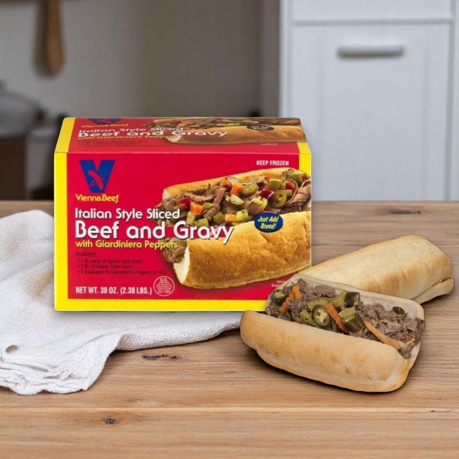 A Vienna Beef Italian Beef Kit – Serves 4 sits on a counter beside two Chicago-style Italian beef sandwiches, one open to reveal the savory filling.