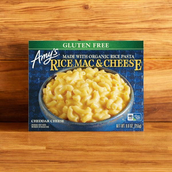 Box of Amy's Kitchen Gluten Free Rice Mac & Cheese, 9 oz. - 4 Count, featuring a comforting meal choice with cheddar cheese, set against a wooden backdrop.