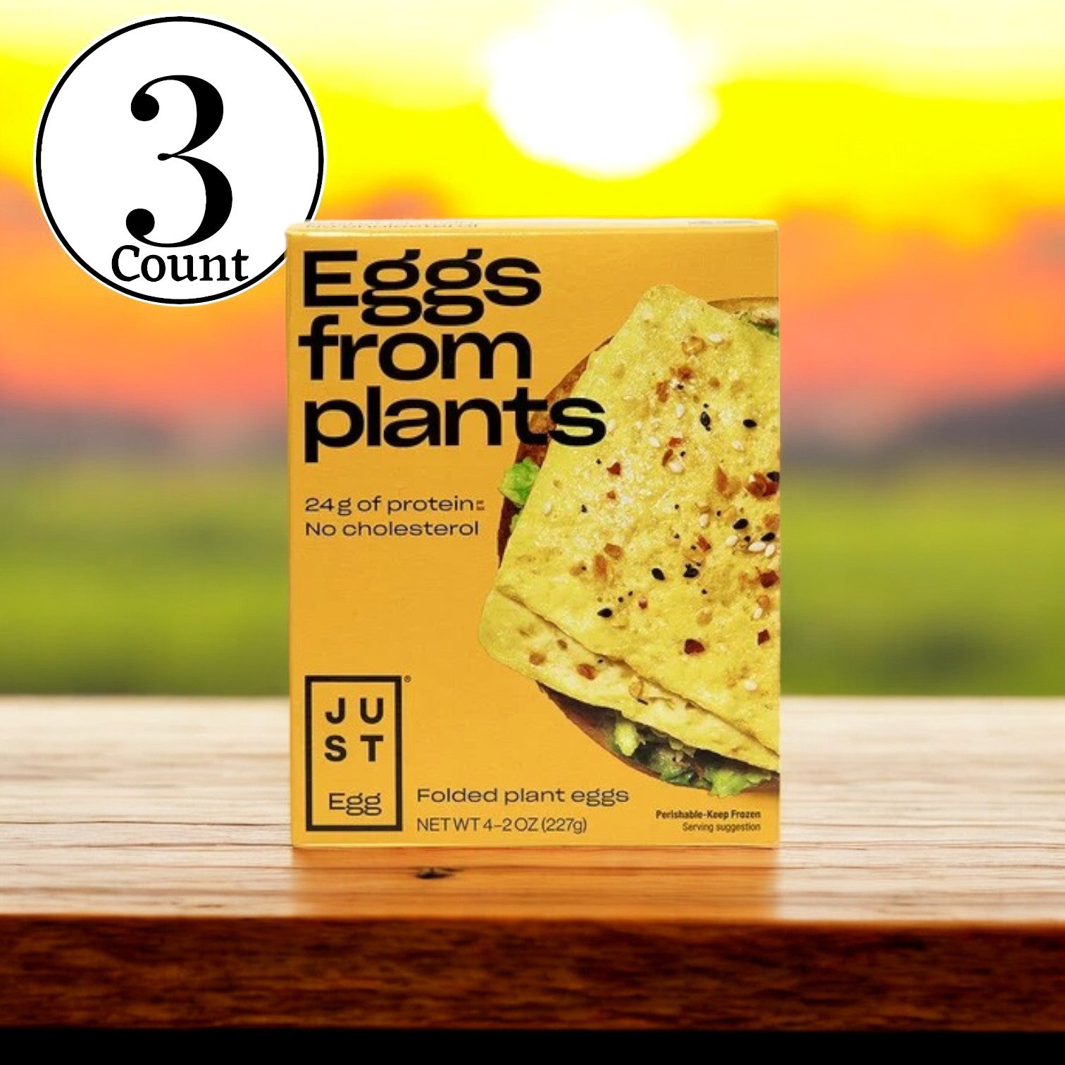 A pack of JUST Egg Folded, a plant-based egg alternative by Just Egg, showcases 24g of protein and is cholesterol-free, all presented in an eco-friendly manner against a sunset backdrop.