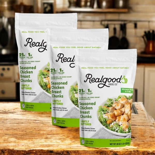 Three bags of Real Good Foods Lightly Buttered Chicken Breast Nuggets, known for their keto-friendly flavor, are displayed on a wooden kitchen counter.