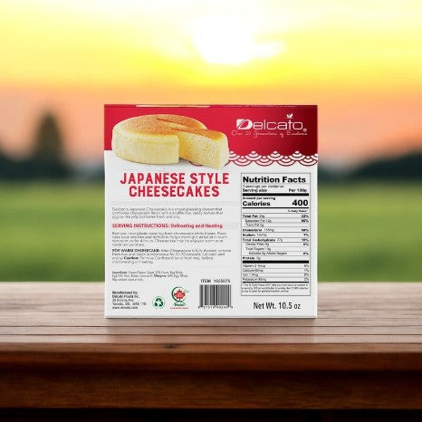 A box of Kirkland Signature Delcato Japanese Style Cheesecake-2-count-1 Pack rests on a wooden table, featuring its unique take on the classic dessert. Its light, fluffy texture is detailed with nutrition facts and serving instructions for convenience.