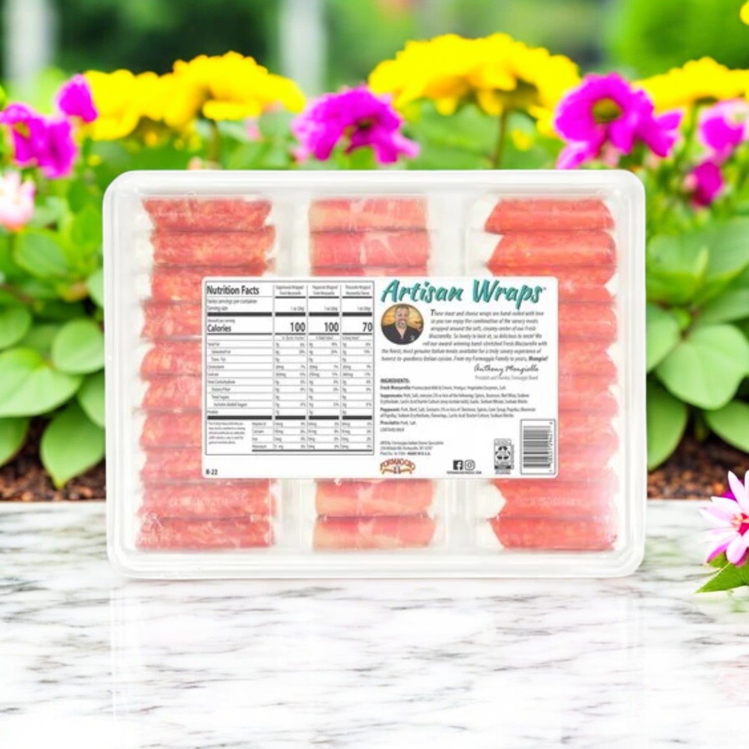 A package of Easy Lunches Formaggio Artisan Wraps, 22 oz. - 3 Count, is displayed on a marble surface with colorful flowers. The packaging includes nutritional info and a label for individually wrapped items featuring delicious mozzarella cheese.