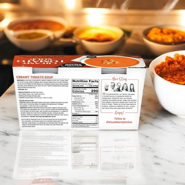 A 24 oz package of Blount's Family Kitchen Creamy Tomato Soup, by Blount Fine Foods, sits on a marble countertop amid steaming bowls. The packaging highlights its homemade taste and quality ingredients, making it a comforting delight.