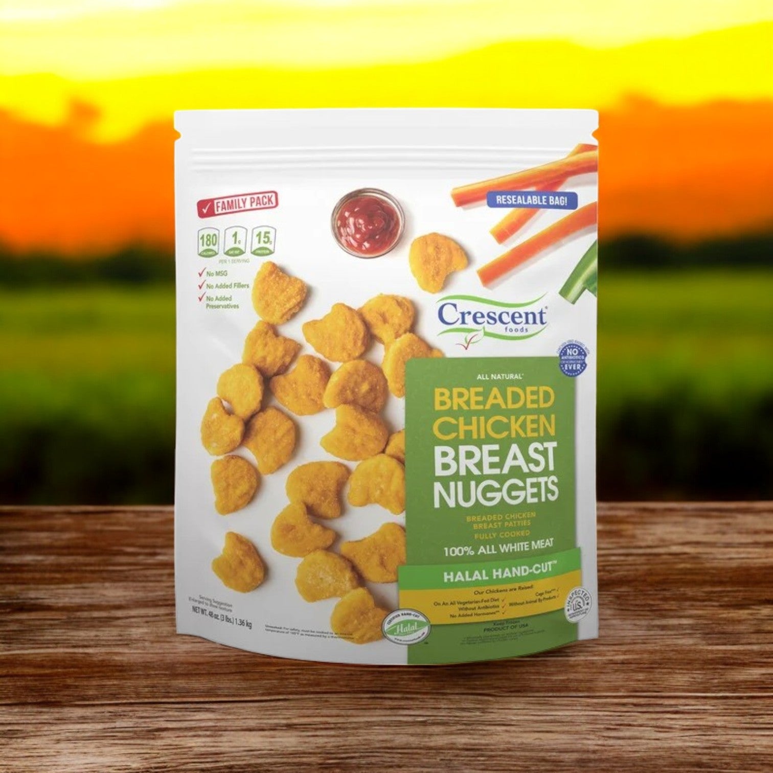 A resealable bag of Crescent Foods Halal All Natural Chicken Breast Nuggets, 3 lbs, is placed on a wooden surface with a sunset field in the background.