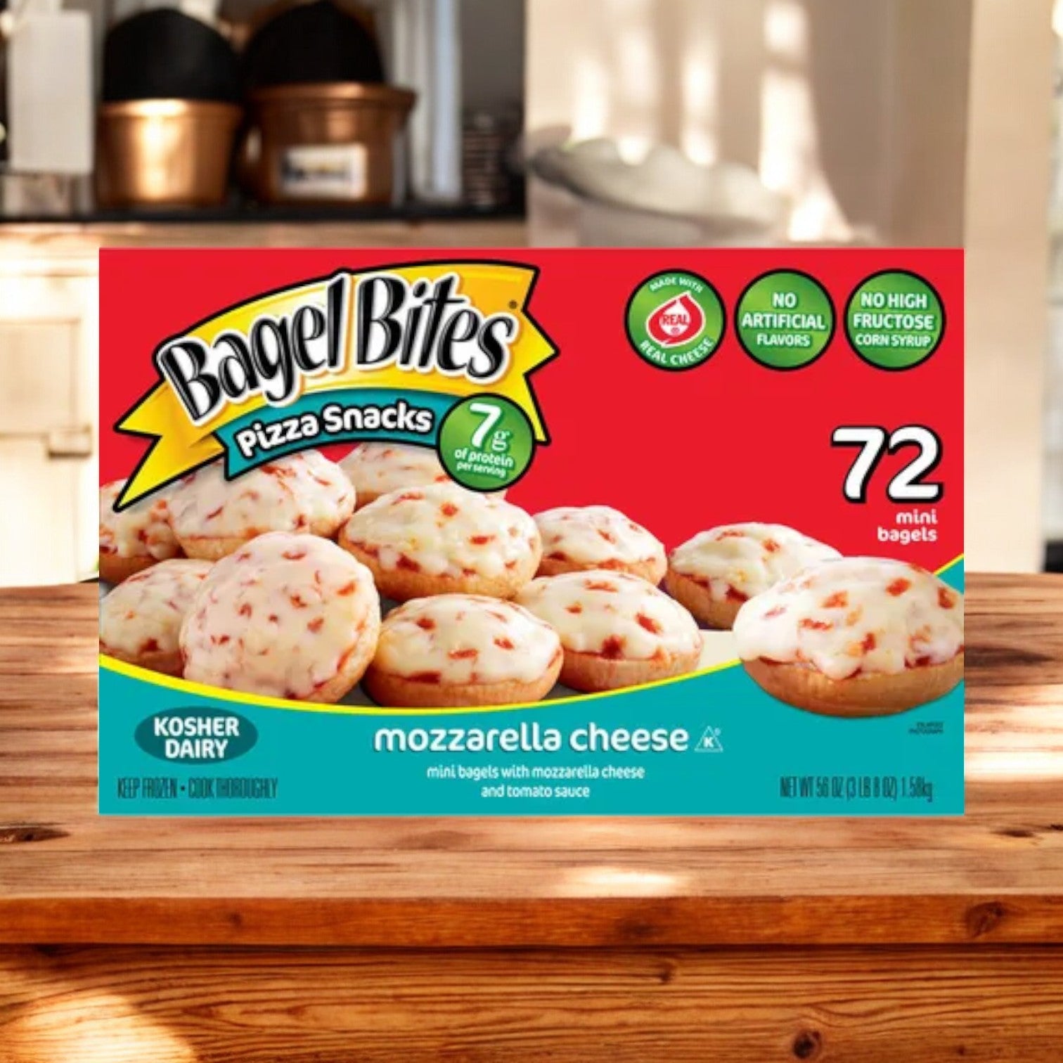 A box of Bagel Bites Mozzarella Cheese Mini Pizza Bagel Frozen Food Snacks -72 Count from Easy Lunches sits on a wooden table. The box features an image of the frozen snacks, indicating 72 mini bagels with mozzarella cheese and tomato sauce.