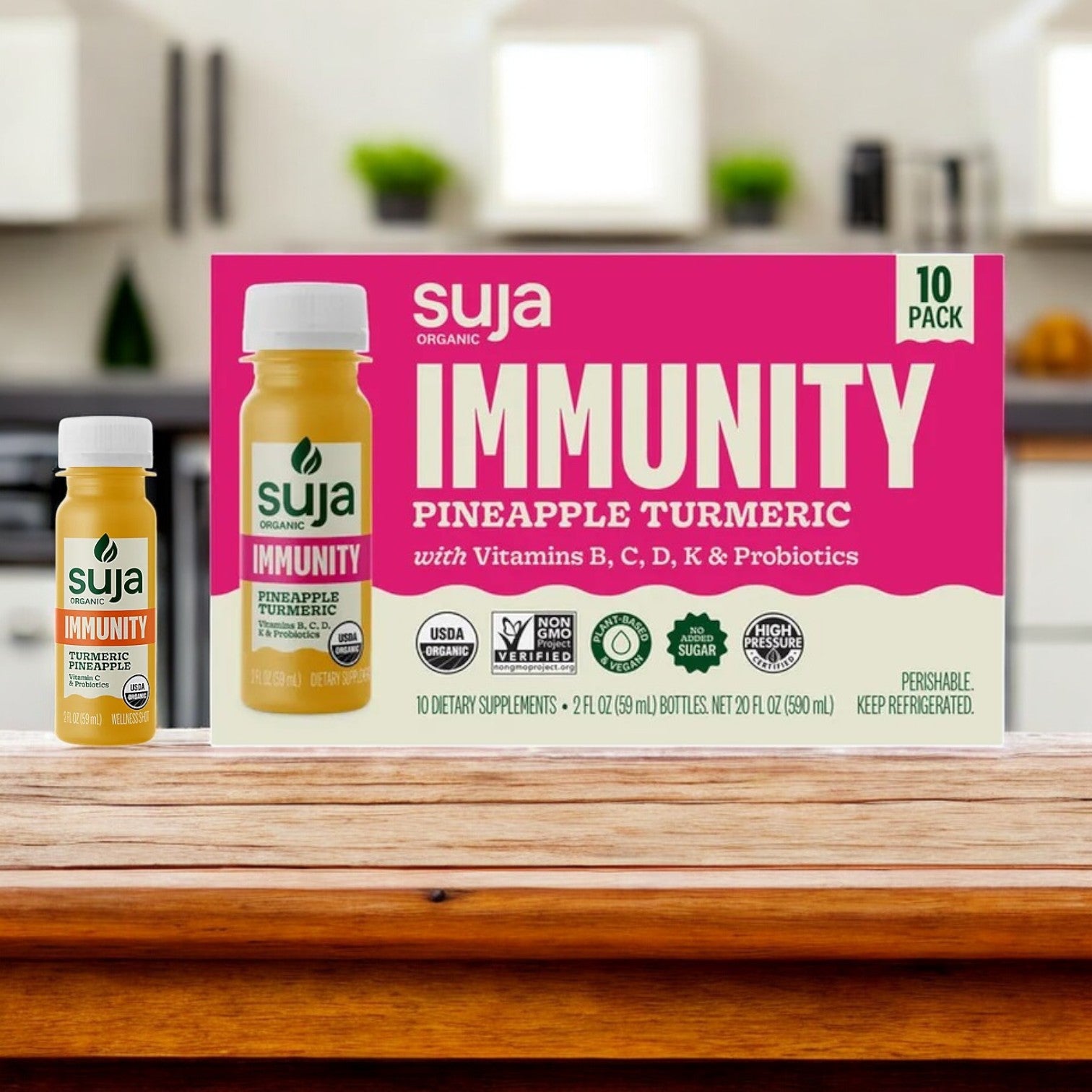 Suja Organic Immunity Defense Shots (10-count, 1 pack) sit on a wooden surface with pineapple and turmeric, featuring vibrant labels that emphasize vitamins, probiotics, and immune support. Perfect for your daily wellness boost.