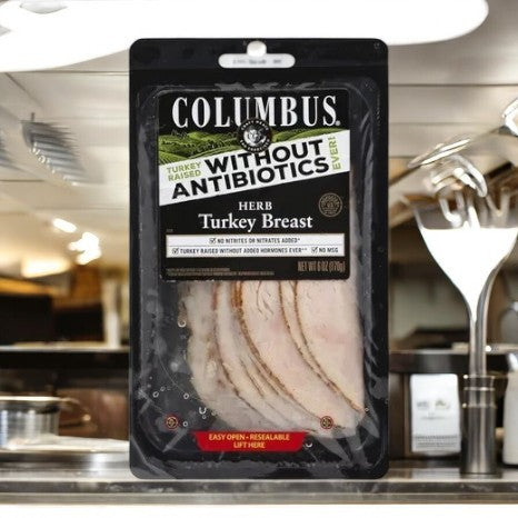 A package of Colombus Herb Roasted Turkey Breast - 1 Count, a nutritious option free from antibiotics, beautifully showcased in a kitchen environment. This is gourmet deli meat at its best.