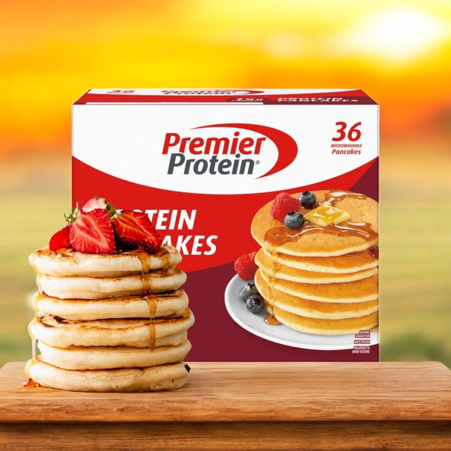 A stack of protein-rich pancakes with strawberries and syrup is attractively set in front of a Premier Protein Pancakes – 36-Count box, against a blurred outdoor backdrop. These delicious pancakes make an ideal low-sugar breakfast.