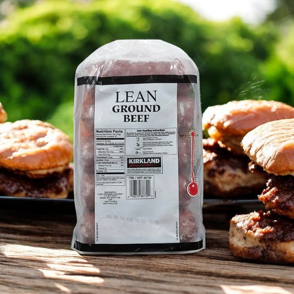 A pack of Kirkland Signature Lean Ground Beef sits enticingly in front of a plate of cooked burgers outdoors—ideal for meal prepping your next delicious feast.