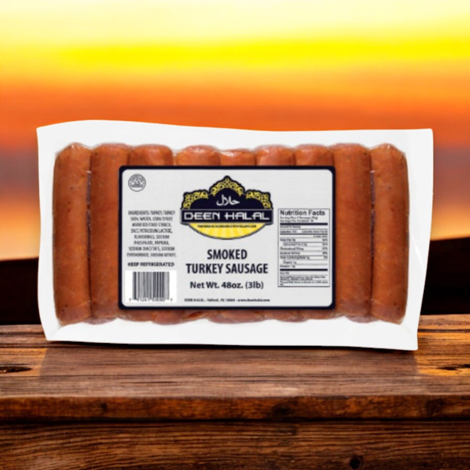 A 3 lb package of Deen Halal Mild Turkey Sausage, made from premium turkey, rests on a wooden surface against a sunset backdrop.