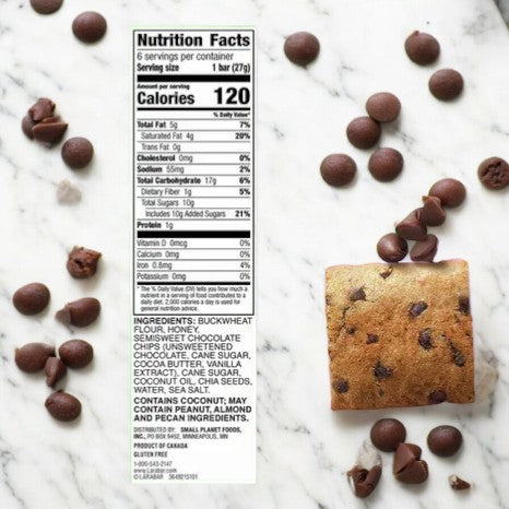 The nutrition facts label and ingredient list for the LÄRABAR Kid Gluten Free Bar Chocolate Chip Cookie, 1.6 oz - 1 Count are displayed. Nearby, a square chocolate chip bar and scattered chocolate chips rest on a marble surface, emphasizing Larabar's commitment to clean eating principles.