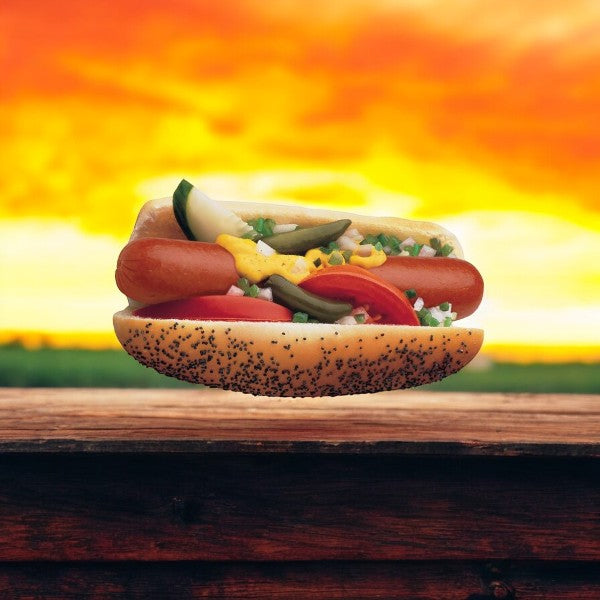 A Vienna Beef Frank nestled in a poppy seed hot dog bun, topped with mustard, tomato slices, and relish, set against a vibrant sunset background.