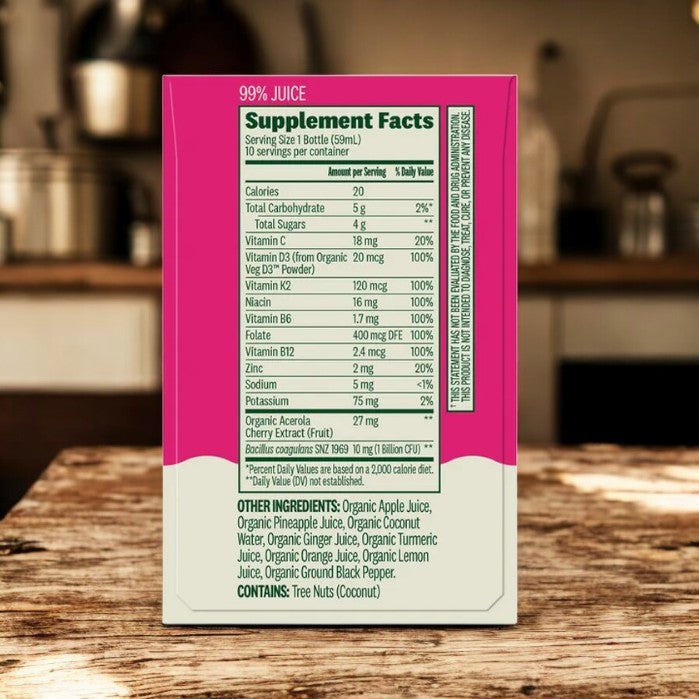 The back of a Suja Organic Immunity Defense Shots box displays supplement facts and ingredients, with a blurred kitchen counter in the background.