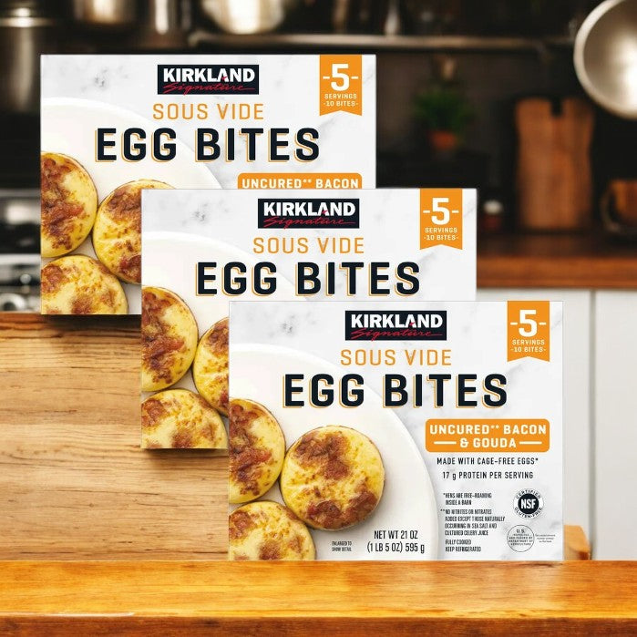 Three boxes of Kirkland Signature Uncured Bacon and Gouda Egg Bites, each with 10 servings, rest on a wooden surface. Made from cage-free eggs, they are a high-protein breakfast option for a delicious start to your day.